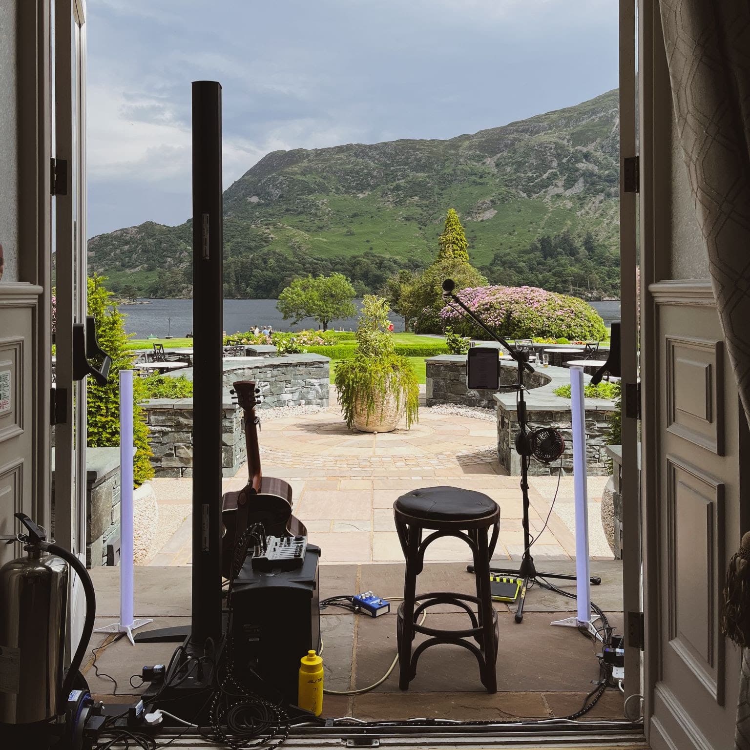 PA, stool and acoustic guitar set up in an open doorway overlooking a Scottish loch and hillside
